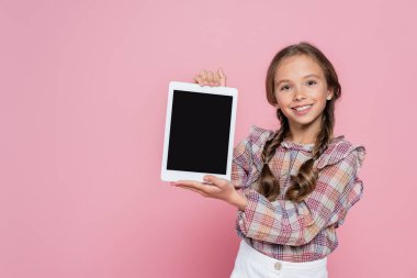 Kareli bluzlu gülümseyen kız pembe ekranda boş ekranlı dijital tablet gösteriyor