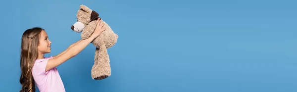 Вид Сбоку Веселого Малыша Смотрящего Мягкую Игрушку Изолированную Синем Баннере — стоковое фото