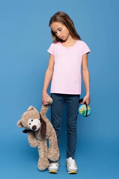 Triste Garoto Com Globo Olhando Para Ursinho Pelúcia Fundo Azul — Fotografia de Stock