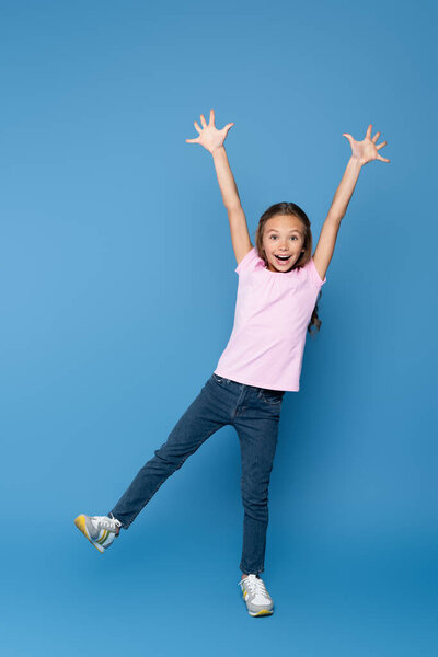 Excited child looking at camera on blue background 
