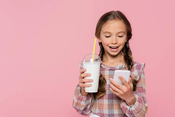 Uśmiechnięty Dzieciak Pomocą Smartfona Trzymając Milkshake Odizolowany Różowo — Zdjęcie stockowe