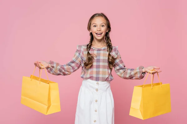 Ragazzo Positivo Con Borse Della Spesa Gialle Isolate Rosa — Foto Stock