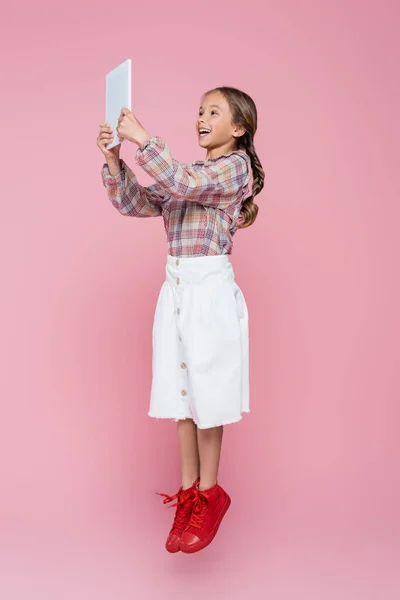 Aufgeregtes Mädchen Stilvoller Kleidung Schwebt Mit Digitalem Tablet Auf Rosa — Stockfoto