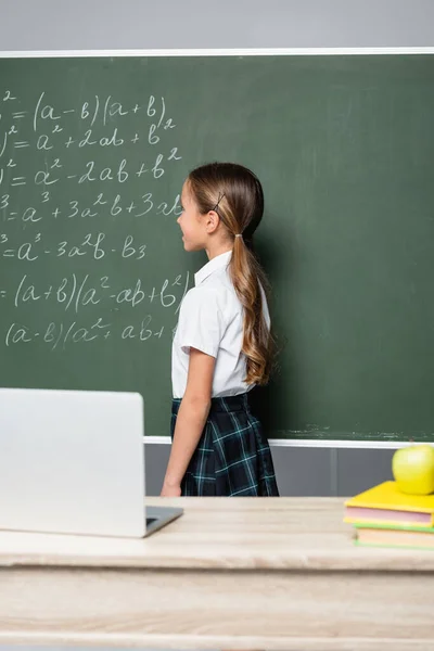 Schoolgirl Standing Chalkboard Equations Desk Laptop — Stock Photo, Image