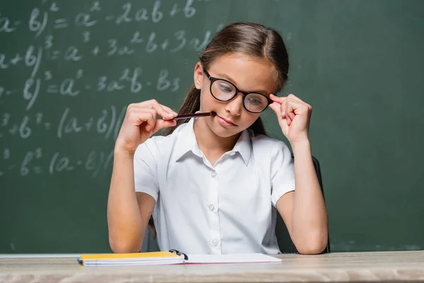 Pensiv Skolflicka Hålla Penna Samtidigt Tänka Nära Anteckningsbok Klassrummet — Stockfoto