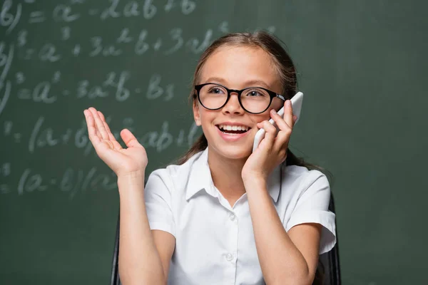 Vrolijk Schoolmeisje Praten Smartphone Buurt Wazig Schoolbord — Stockfoto