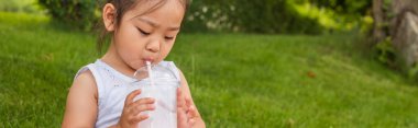 Sarı elbiseli Asyalı çocuk samandan lezzetli bir milkshake içiyor.
