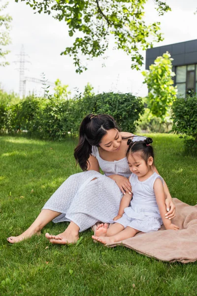 アジア系の母親は幼い娘をピクニック毛布の上に座って — ストック写真