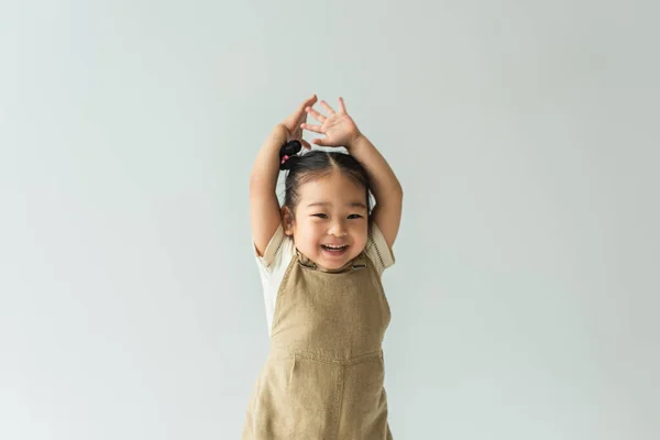Ευτυχισμένο Ασιατικό Κοριτσάκι Σηκωμένα Χέρια Απομονωμένο Στο Γκρι — Φωτογραφία Αρχείου