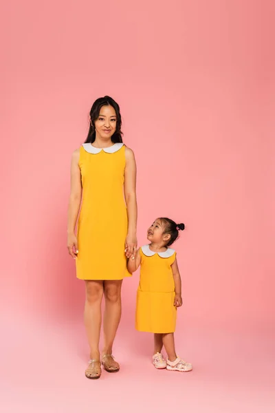 陽気なアジア人女性保持手とともに幼児娘オンピンク — ストック写真