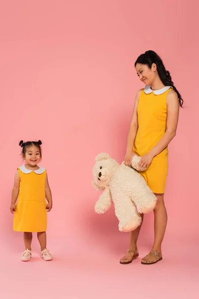 Pleased Asian Woman Holding Teddy Bear Looking Happy Toddler Daughter — Stock Photo, Image