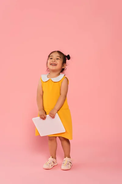 Full Length Cheerful Asian Toddler Kid Yellow Dress Holding Digital — Stock Photo, Image