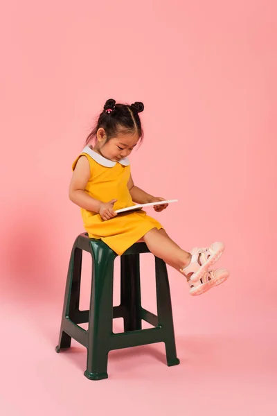 Full Length Pleased Asian Toddler Kid Yellow Dress Sitting Chair — Stock Photo, Image