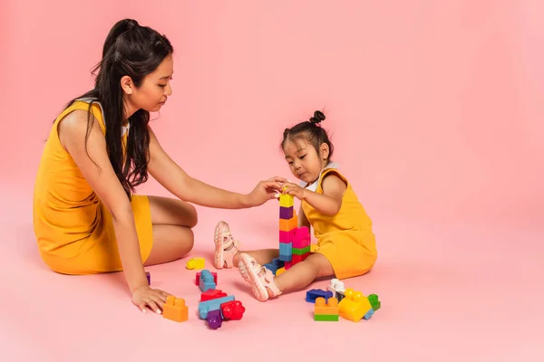 亚洲妇女和女儿坐在粉红上玩积木游戏 — 图库照片