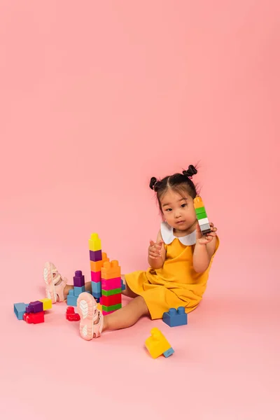 Brunette Asian Girl Yellow Dress Playing Building Blocks Pink — Stock Photo, Image