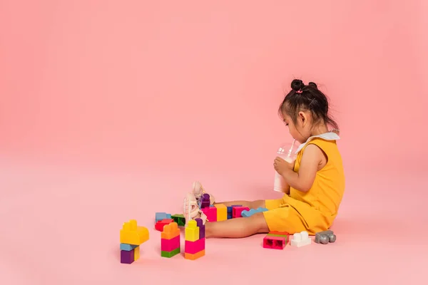 Sarı Elbiseli Asyalı Küçük Kız Pembe Renkli Yapı Taşlarının Yanında — Stok fotoğraf