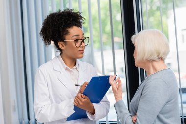 Afro-amerikan doktor. Hastanedeki hastayla konuşuyor. 