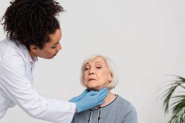 African american doctor checking neck of senior patient  clipart