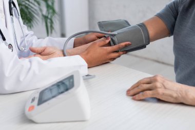 Hasta koluna tonometre takan Afrikalı Amerikalı bir doktor. 