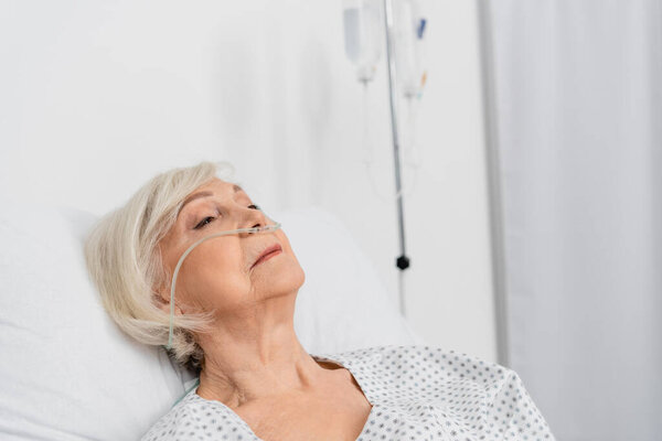Elderly patient with nasal cannula lying in hospital ward 