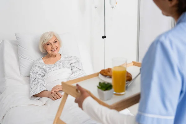 Glimlachende Senior Vrouw Zoek Naar Afrikaanse Amerikaanse Verpleegster Met Voedsel — Stockfoto