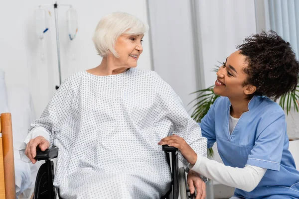 Leende Afrikansk Amerikansk Sjuksköterska Tittar Patient Rullstol Sjukhus — Stockfoto