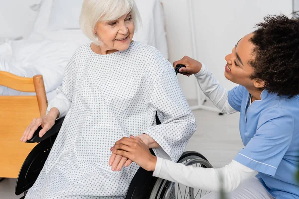 Улыбающаяся Африканская Американская Медсестра Держит Руку Пожилого Пациента Инвалидном Кресле — стоковое фото