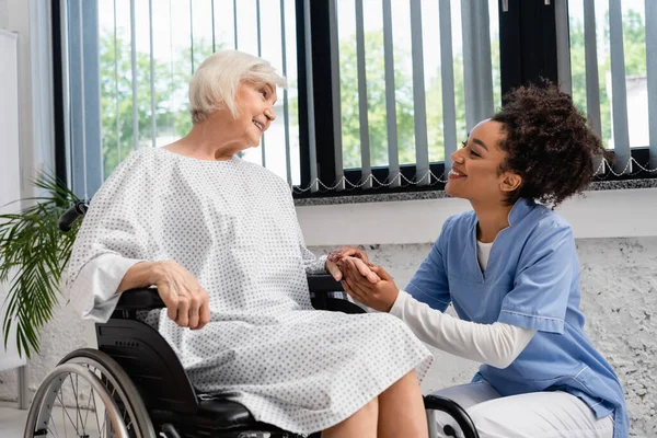 Африканская Американская Медсестра Держит Руку Улыбающуюся Пожилую Женщину Инвалидном Кресле — стоковое фото