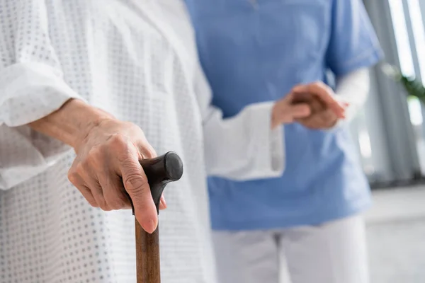 Beskuren Bild Äldre Patient Som Håller Käpp Nära Suddig Sjuksköterska — Stockfoto