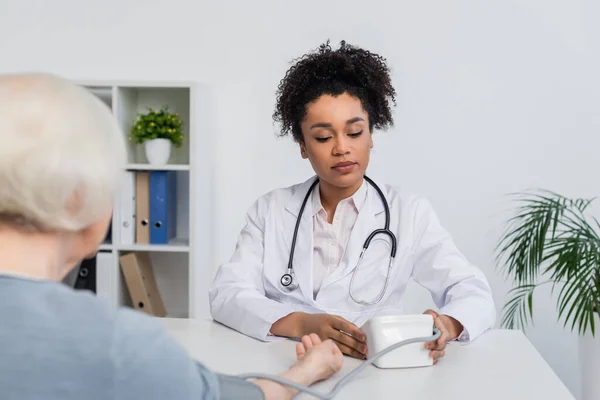 Médico Afroamericano Mirando Tonómetro Cerca Paciente Borroso Clínica — Foto de Stock