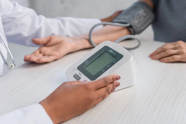 非洲裔美国医生带着电子血压计接近模糊病人的剪影 — 图库照片