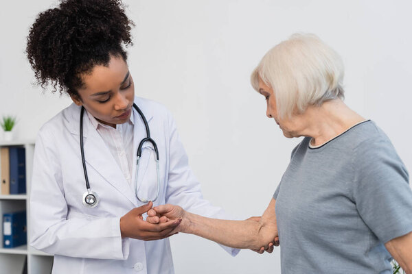 African american doctor with stethoscope touching arm of patient 