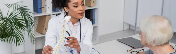 Fisioterapeuta Afro Americano Apontando Para Modelo Coluna Vertebral Perto Paciente — Fotografia de Stock