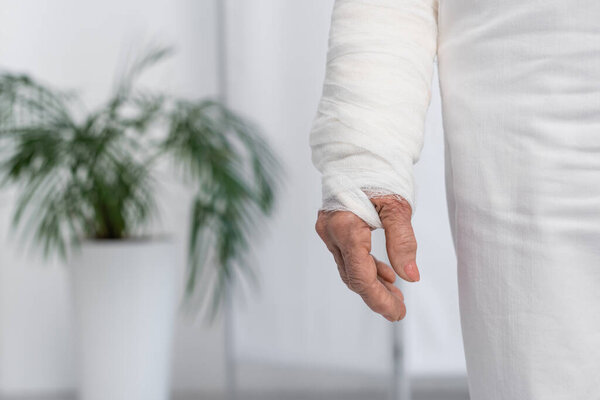 Cropped view of elderly woman with plaster bandage on arm in clinic 