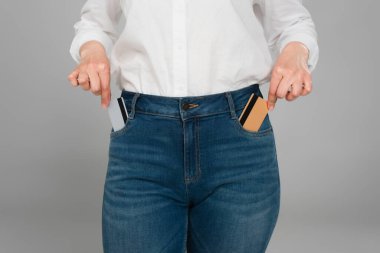 Gri renkli kot pantolon ceplerinden kredi kartı alan kadının kısmi görüntüsü