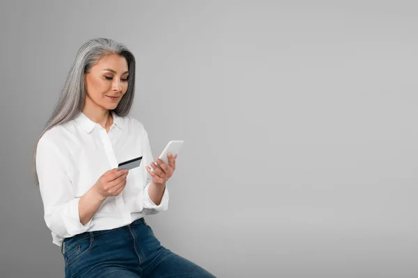 Stilvolle Asiatische Frau Sitzt Mit Kreditkarte Und Handy Isoliert Auf — Stockfoto