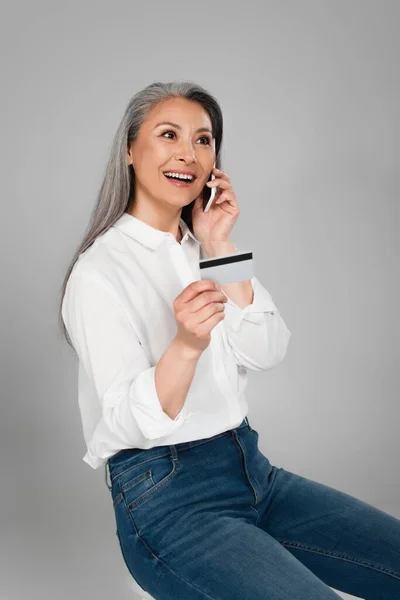 Happy Asian Woman Credit Card Talking Mobile Phone Isolated Grey — Stock Photo, Image