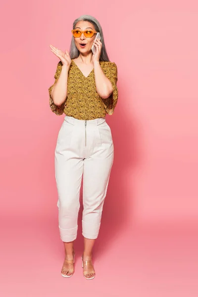 Astonished Asian Woman White Pants Talking Smartphone Pointing Hand Pink — Stock Photo, Image