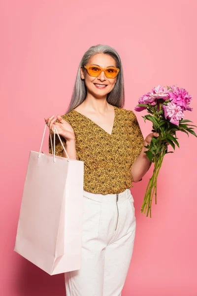 Pleased Asian Woman Stylish Sunglasses Holding Peonies Shopping Bag Pink — Stock Photo, Image