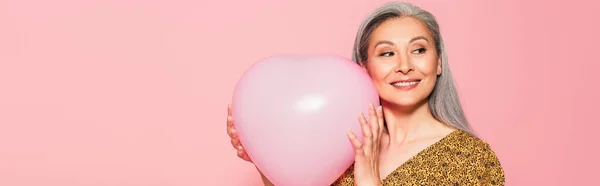 快乐的亚洲女人 有着心形气球 在粉红色的横幅上孤零零地望着远方 — 图库照片
