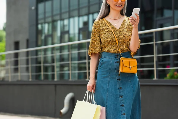 Částečný Pohled Ženu Středního Věku Nákupními Taškami Pomocí Mobilního Telefonu — Stock fotografie