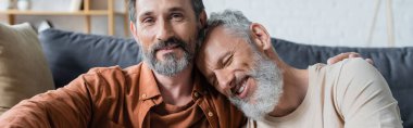 Homoseksüel adam gülümseyen partneri kucaklıyor. 