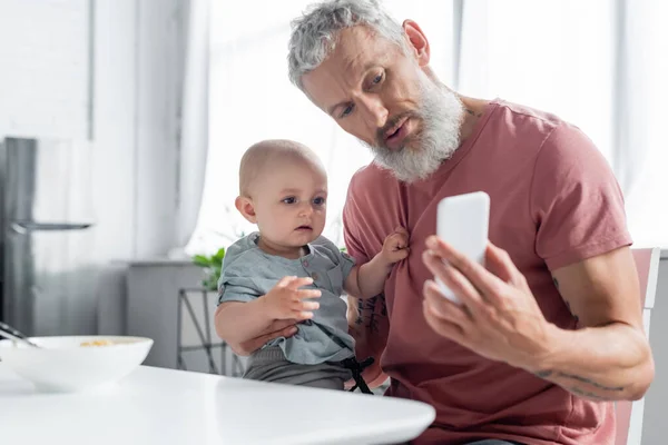 成熟的父亲拿着智能手机靠近女儿 早餐模糊不清 — 图库照片