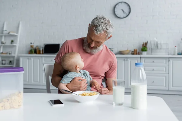 Hombre Maduro Sosteniendo Bebé Hija Cerca Teléfono Inteligente Desayuno Cocina — Foto de Stock