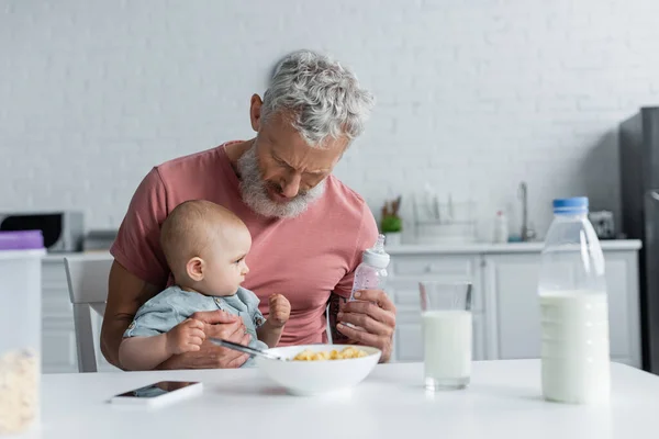 Mature Man Holding Baby Bottle Daughter Breakfast Kitchen — Stock Photo, Image