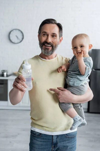 Gülümseyen Adam Kucağında Bebek Kızıyla Bebek Şişesiyle Evde — Stok fotoğraf