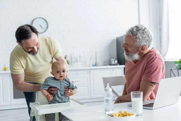 Smiling Homosexual Couple Looking Baby Daughter Laptop Breakfast — Stock Photo, Image