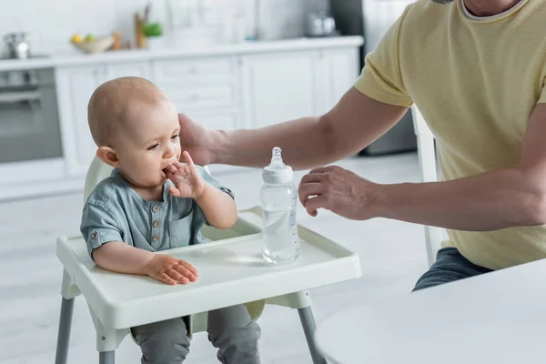 Uomo Toccare Bambino Figlia Vicino Bottiglia Acqua Sul Seggiolone — Foto Stock