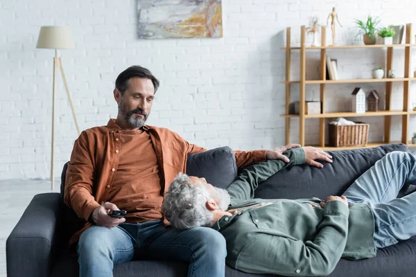 Homosexual couple with remote controller on couch