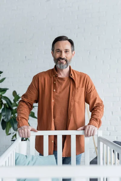 Sonriente Hombre Pie Cerca Cama Bebé Casa — Foto de Stock